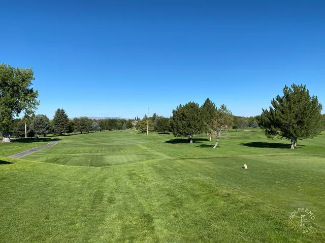 A golfer hitting a shot at Riverside Country Club, with the fairway and mountains ahead.