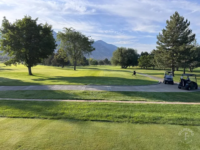 A golfer putting on a green at Riverside Country Club, with the mountains behind the hole.