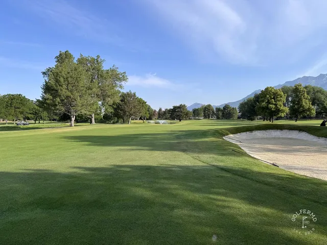 A green and flagstick at Riverside Country Club, with a sand bunker guarding the front.