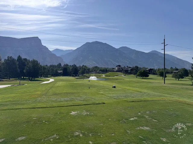 A wide hole at Riverside Country Club, with trees along the fairway and mountains on the horizon.