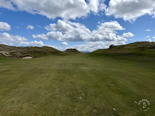 A green and flagstick on the Sandy Hills, with a bunker in front and the ocean behind the hole.