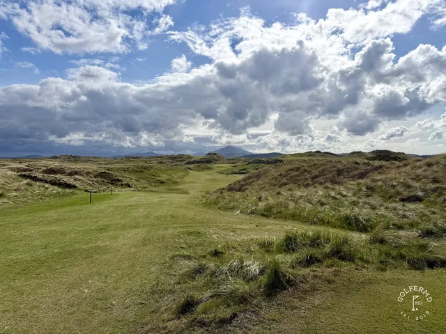 A fairway and green on the Sandy Hills, with a bunker in the foreground and the ocean beyond.