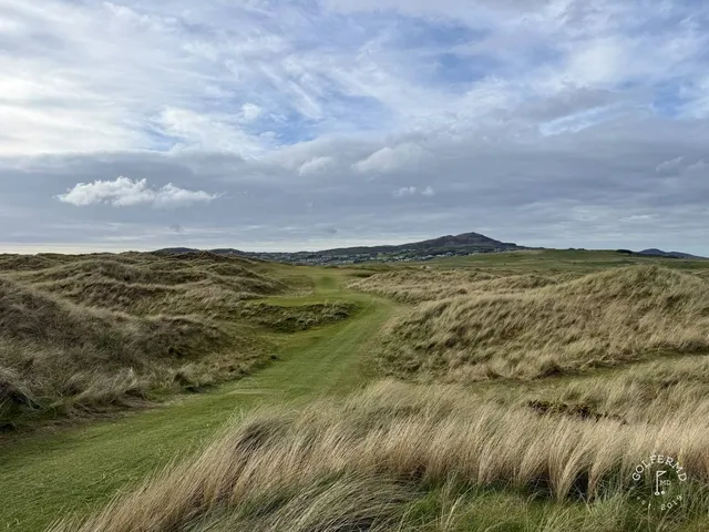A green and flagstick on the Sandy Hills, seen from a rise, with the Atlantic behind the hole.