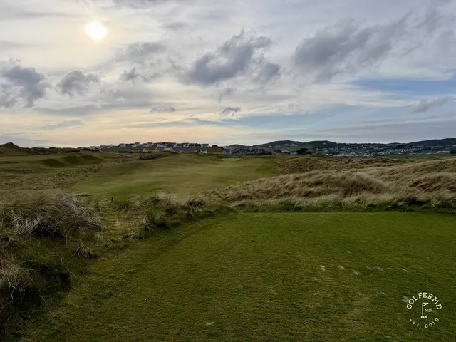 A close view of a green on the Sandy Hills, with sand in front and the water beyond.