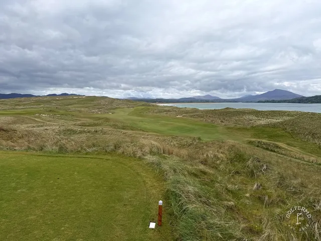 A golfer hitting a shot on St. Patrick's, with the fairway and the water ahead.