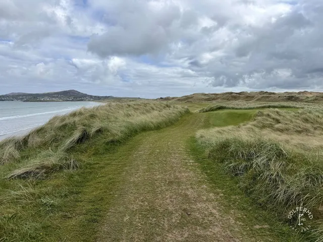 A green and flagstick on St. Patrick's above the water, with a bunker short of the green.