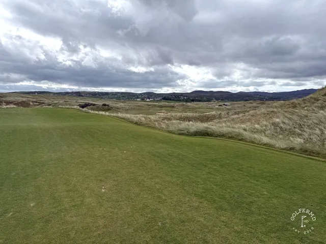 A golfer putting on a green on St. Patrick's, with the ocean beyond the hole.