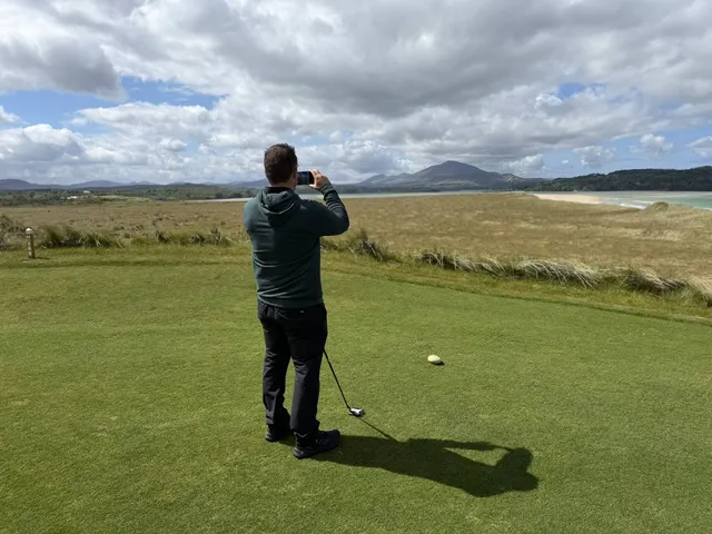 A green and flagstick on St. Patrick's, seen from a rise, with the Atlantic behind the hole.