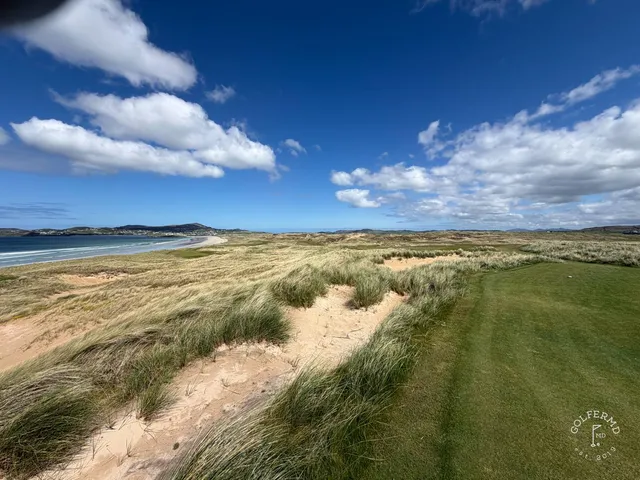 A green and flagstick on St. Patrick's, seen from the tee, with the ocean behind the hole.