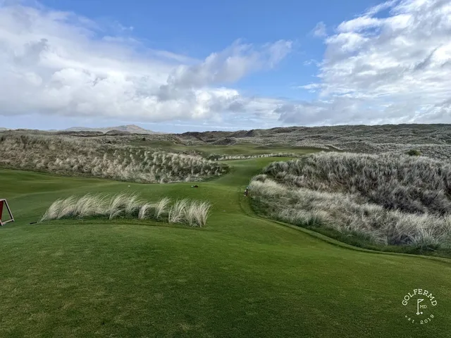 A golfer hitting a shot from the fairway on St. Patrick's, with the mountains ahead.