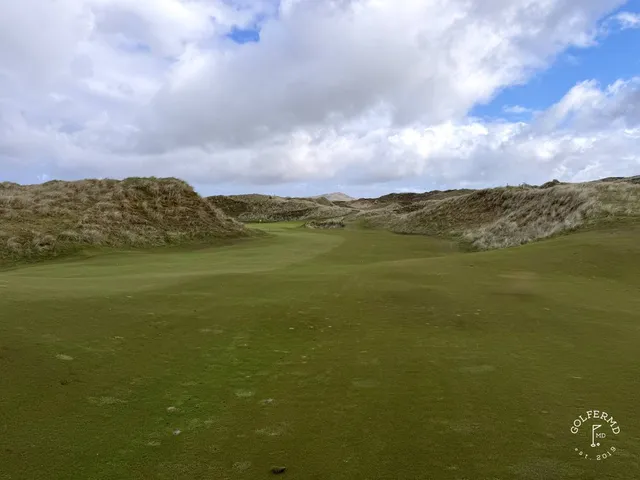 A fairway on St. Patrick's lined with beach grass, with the ocean in the distance.