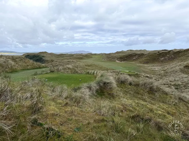 A group of golfers on St. Patrick's, with the course and the bay behind them.