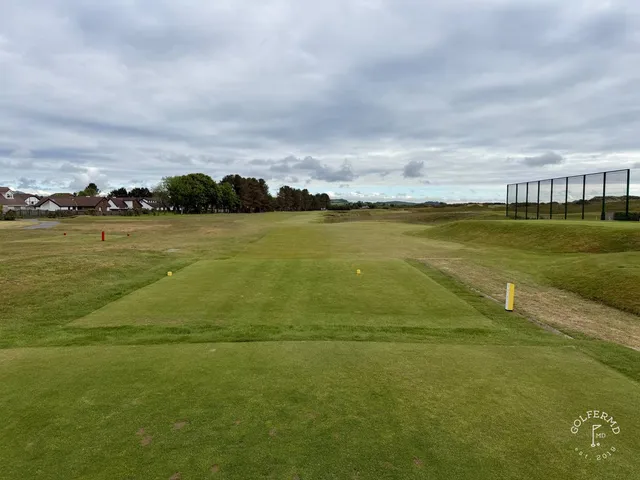 A golfer hitting a shot on the Annesley Links, with the dunes and the mountains ahead.