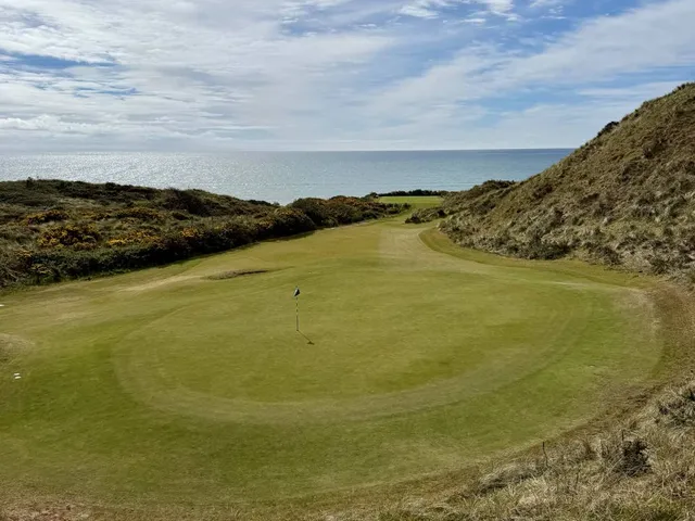 A golfer putting on the Annesley Links, with the dunes behind the green.