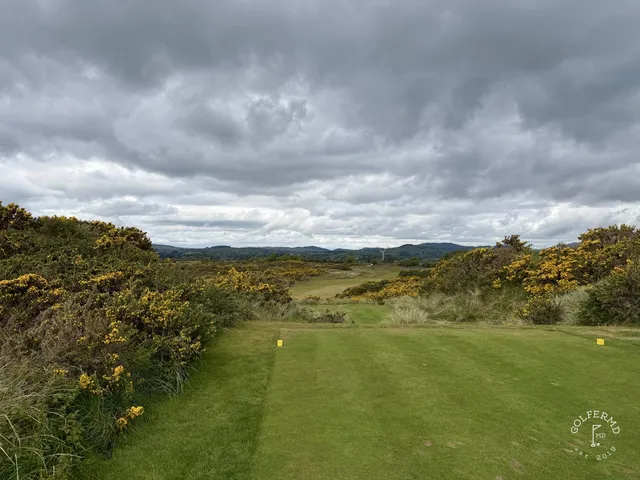 Golfers walking a fairway on the Annesley Links, with the bay beside the hole.