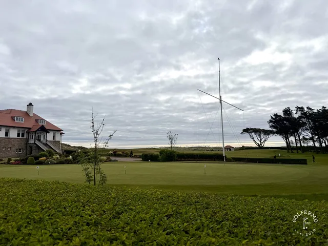 A green and flagstick on the Annesley Links, with a bunker in front and the mountains beyond.