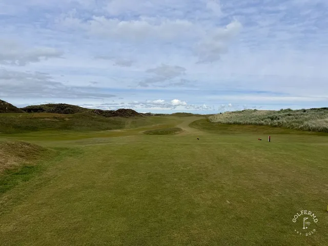 A golfer hitting a shot at Royal County Down, with the dunes and the mountains ahead.