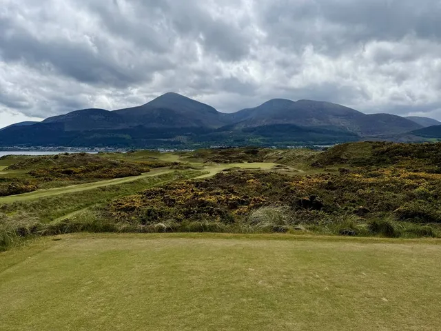 A fairway at Royal County Down bending through the dunes toward a distant green.