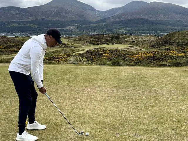 A wide panorama of Royal County Down, gorse, sand, and the Mournes.