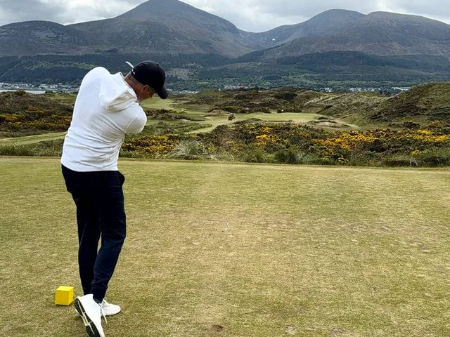 A green and flagstick at Royal County Down seen from the fairway, with the mountains on the horizon.