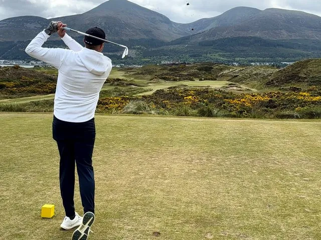 A golfer putting at Royal County Down, with the dunes behind the green.