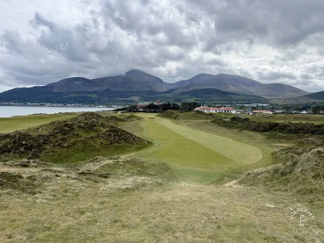 An elevated view across Royal County Down, fairways and gorse in front of the Mournes.