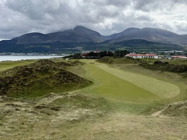 A tee shot at Royal County Down, the fairway dropping toward a green in the dunes.