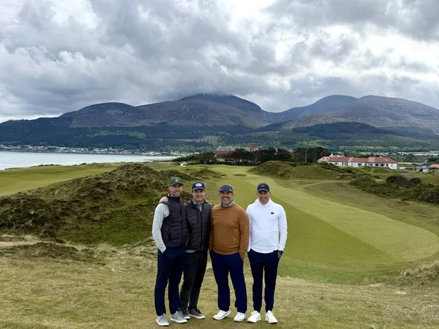 Golfers walking a fairway at Royal County Down, with the mountains beside the hole.