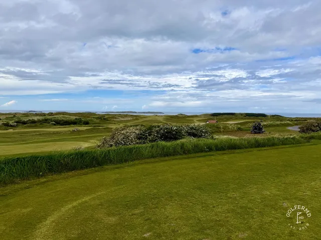 A wide view of the links at Royal Portrush, with the fairway, the dunes, and the sea.