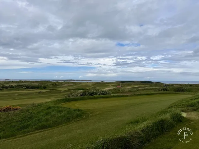 A golfer hitting a shot at Royal Portrush, with the ocean ahead.