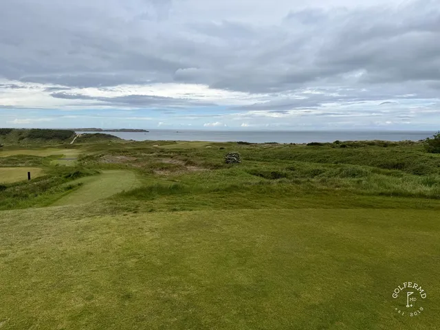 A green at Royal Portrush set above the beach, with the flagstick and the water beyond.