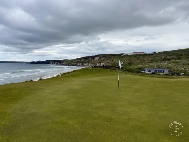 A close view of a flagstick at Royal Portrush, with a pot bunker beside the green.