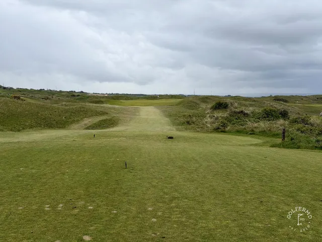 A wide panorama of Royal Portrush, with several holes in the dunes and the ocean beyond.