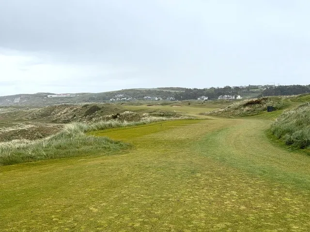 A golfer putting at Royal Portrush, with the dunes behind the green.