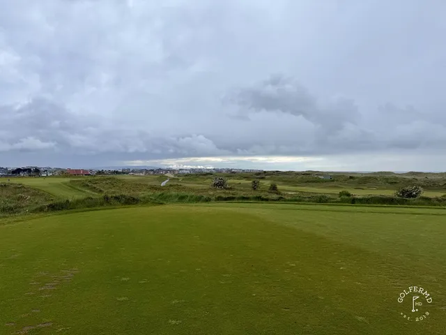 A green at Royal Portrush guarded by sand, with the coastline behind the hole.
