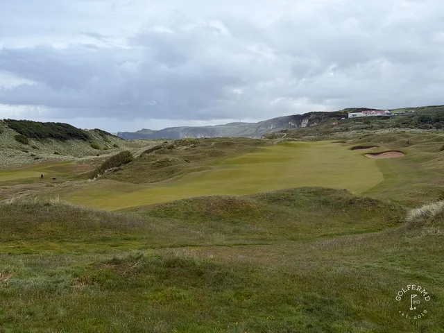 A close view of a green at Royal Portrush, the flagstick framed by marram grass.