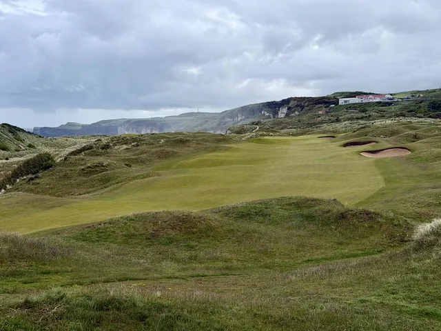Golfers walking a fairway at Royal Portrush, with the ocean beside the hole.