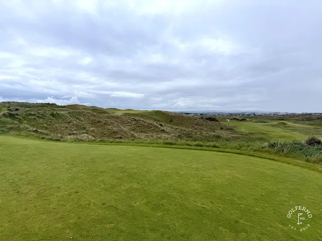 A green and flagstick at Royal Portrush, a deep bunker short of the hole and the dunes behind.
