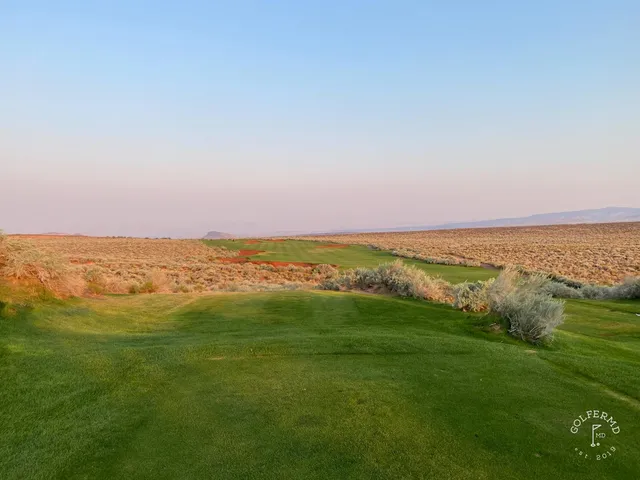 A fairway at Sand Hollow running toward red rock cliffs, with a bunker on the right.