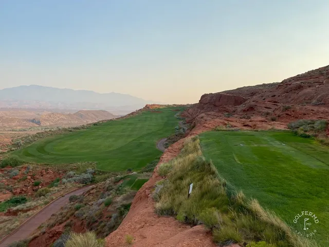 A close view of a flagstick at Sand Hollow, with a bunker and the desert beyond the green.