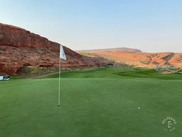 A tee view at Sand Hollow, the fairway dropping toward a green set in the red desert.