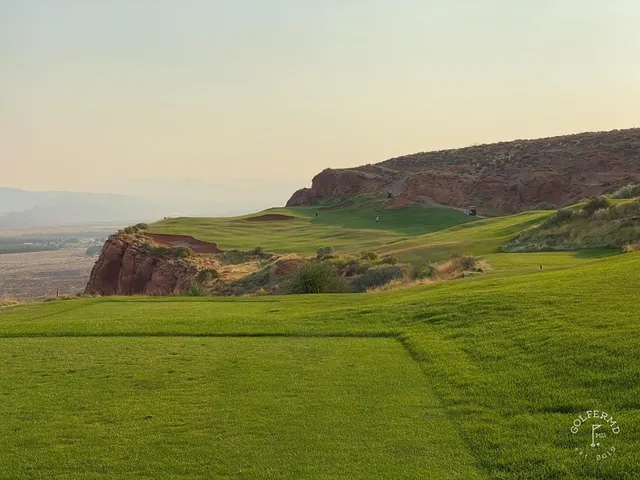 A fairway at Sand Hollow with water in the distance and the red cliffs beyond.