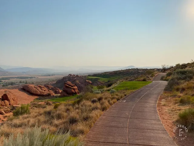A green and flagstick at Sand Hollow, water behind the hole and sand around the green.