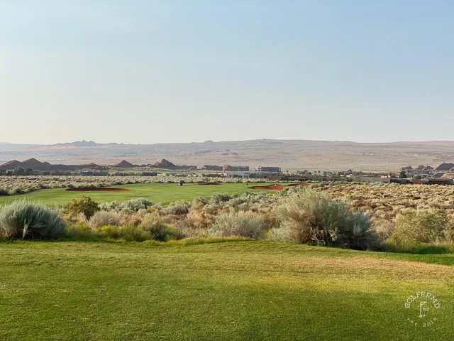 A tee shot at Sand Hollow with sand on both sides and the cliffs ahead of the green.
