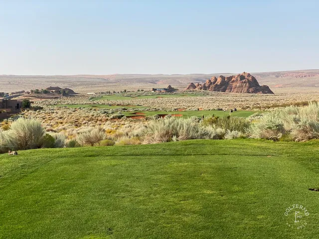 A closer green at Sand Hollow, the flagstick and a deep bunker with the red rock behind.