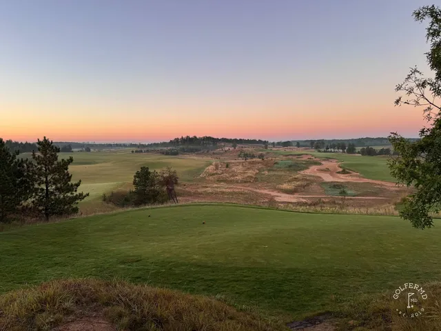 A green and flagstick at Sand Valley, with a bunker in front and the dunes beyond.