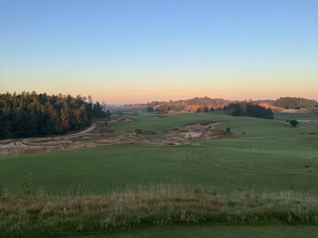 A golfer hitting a shot at Sand Valley, with the sandy fairway ahead.