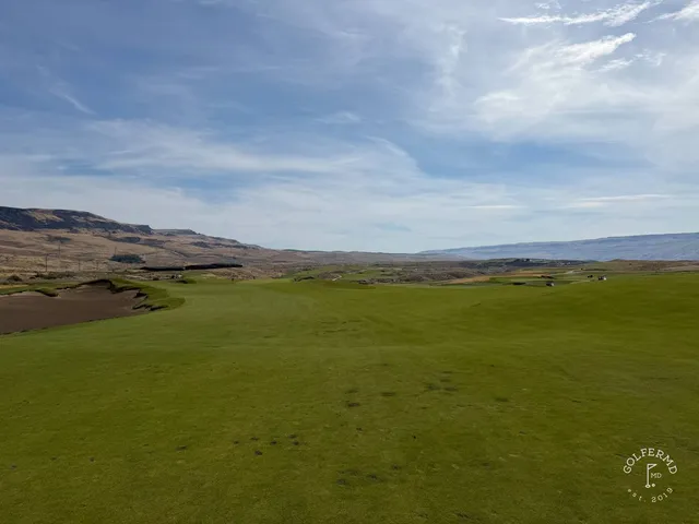 A short hole at Scarecrow, the green set in sandy waste with the mountains behind.
