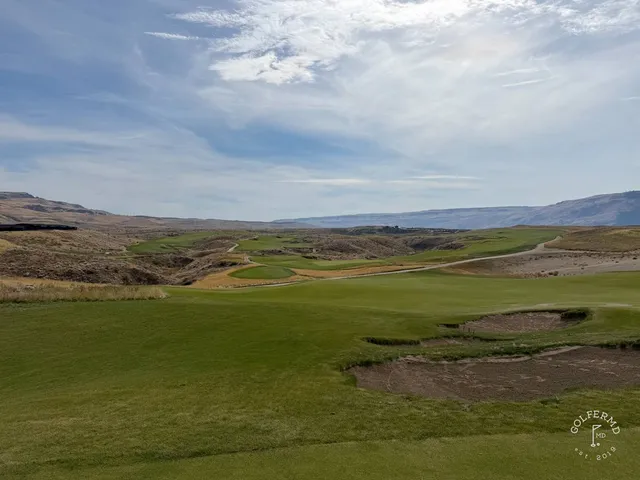 A green and flagstick at Scarecrow, a bunker in front and the hills beyond.