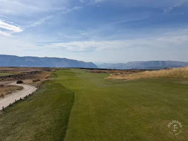 A golfer hitting a shot at Scarecrow, with the sandy hole ahead.